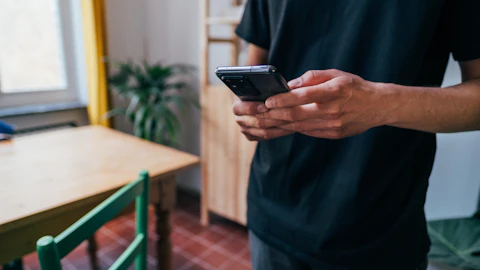 Persona sosteniendo un teléfono inteligente negro en la calle