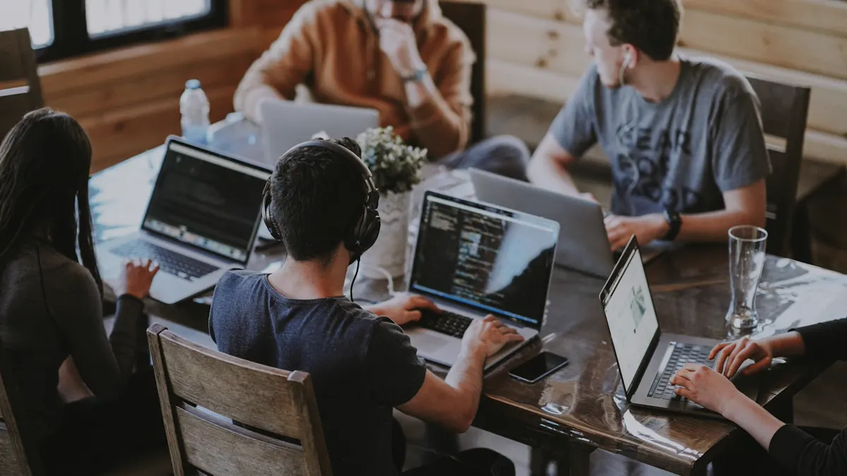 Equipo colaborando alrededor de computadoras y un tablero de trabajo