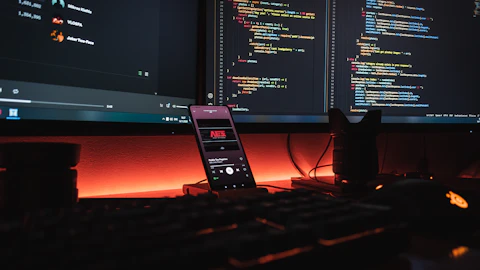 Monitores de computadora y smartphone mostrando código en pantalla