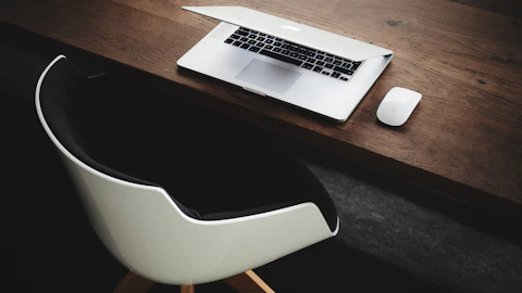 MacBook junto al mouse de la computadora sobre la mesa
