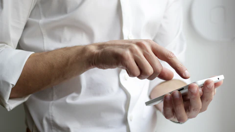 Persona sosteniendo un teléfono inteligente Android blanco con la mano