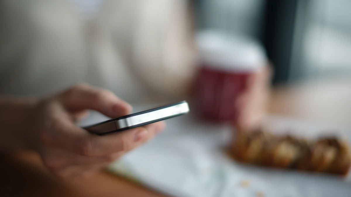 Primer plano de una persona sosteniendo un teléfono gris